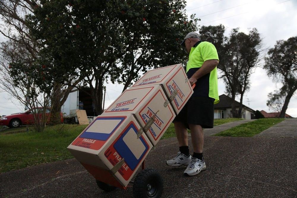 Operatore durante un trasloco con scatole imballate su carrello